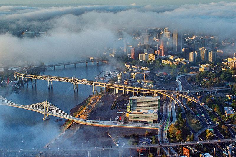 aerial of downtown Portland with clouds floating over buildings and bridges